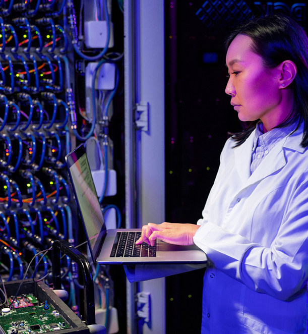 A person holding a laptop computer in a lab coat in a server room